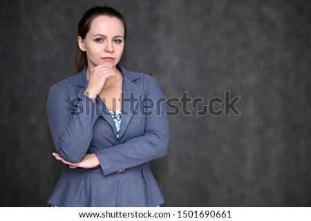 Portrait of a pretty manager woman on a dark background in a gray business suit. Standing right in front of the camera in various poses.