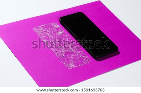Smartphone with broken protective glass on paper background. Side view