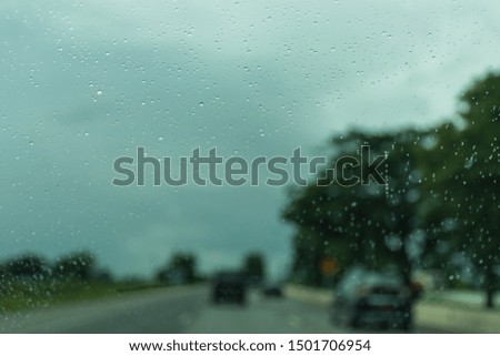 Raindrops on a car glass or windshield, rural life in the rainy season abstract background, water drops on the glass, concept of driving a car,Driving in rain.Selective focus.