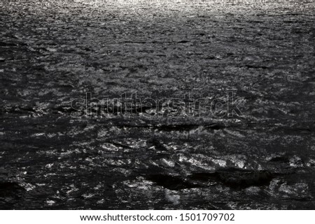 A dark and dramatic water with sun glitter in a stormy day