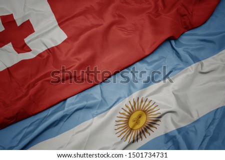 waving colorful flag of argentina and national flag of Tonga . macro