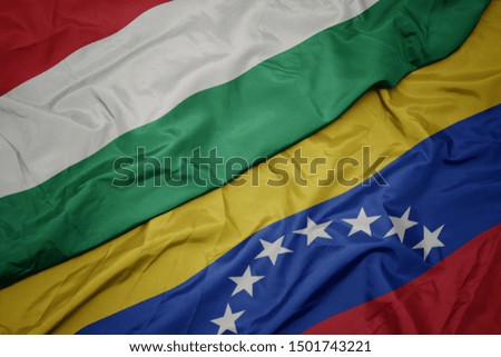 waving colorful flag of venezuela and national flag of hungary. macro