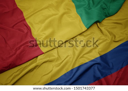 waving colorful flag of colombia and national flag of guinea. macro