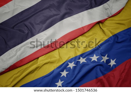 waving colorful flag of venezuela and national flag of thailand. macro