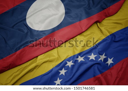 waving colorful flag of venezuela and national flag of laos. macro