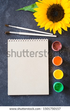 Autumn mock up for greeting card or your notifications. Fall background with empty notebook, paints and sunflower. Top view, flat lay, copy space.