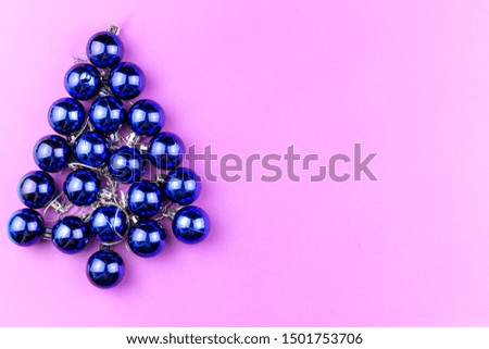 Christmas tree made of round, blue Christmas balls on a pink background with a copy space
