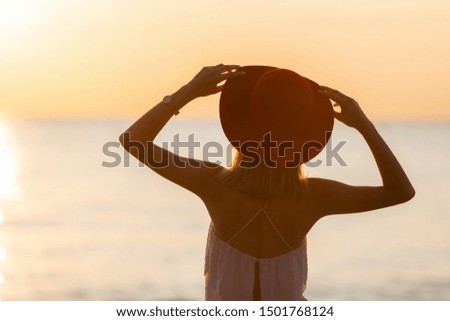 Silhouette of slim girl in hat on the beach