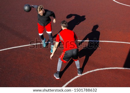 Movement and moment of the dribbling on the basketball court during the match. Athletic lifestyle and basketball competitions. Two young athletes play basketball. Basketball hoop defense and attack.