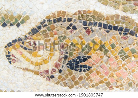 mosaic close-up in brown yellow colors, multi-colored irregular square pieces with white seams, fish silhouette