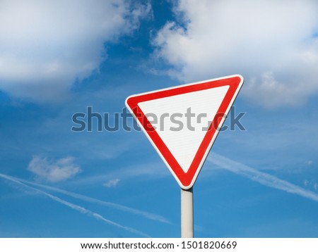 International traffic sign 'Yield sign' or 'Give way'.   Blue sky with some clouds is on background