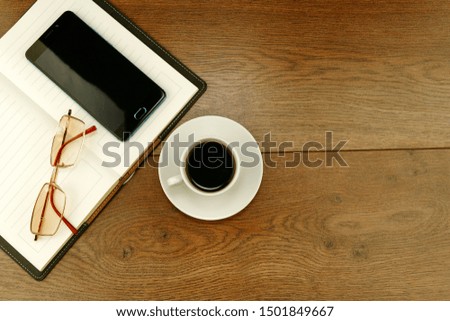 Cup of coffee and stationery on a brown wooden table. Concept of freelance, office work and business
