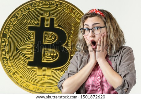 Girl in glasses and a shirt on the background of Bitcoin. Thinking about question, pensive expression, looks incredulous. Change in the growth and fall of cryptocurrency.