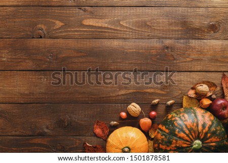 Autumn composition. Pumpkins, fallen leaves, acorns, red berries, walnuts on wooden table. Happy Thanksgiving concept. Flat lay, top view, copy space