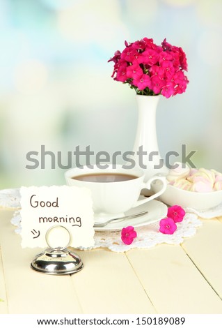 Beautiful bouquet of phlox with cup of tea on table on light background