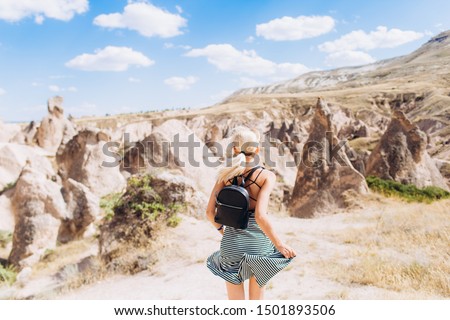 A blonde girl runs across the mountains in Turkey in Cappadocia. Follow me.