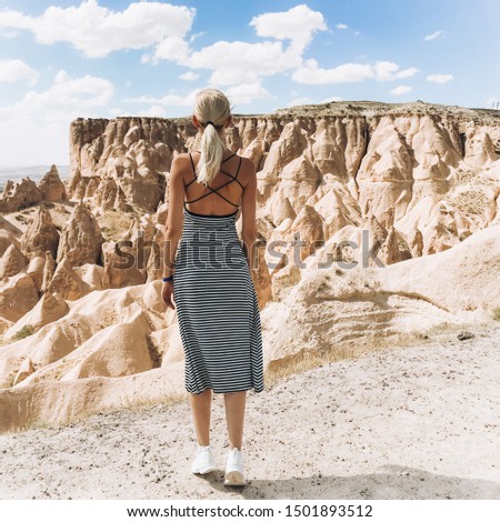 A blonde girl runs across the mountains in Turkey in Cappadocia. Follow me.