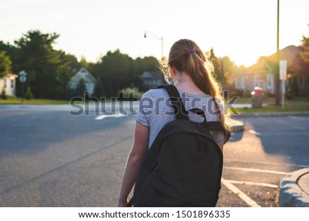 Profile of a teen girl depressed/sad at sunset in a parking lot while wearing a backpack. Royalty-Free Stock Photo #1501896335