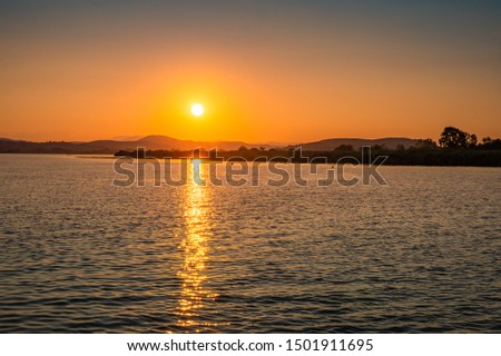 Beautiful sunset behind the famous lake of Ioannina, Greece. Sunset colors at lake Pamvotis boating to the small island. Epirus, Greece. Royalty-Free Stock Photo #1501911695