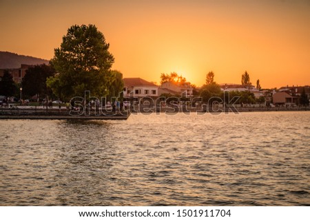 Beautiful sunset behind the famous lake of Ioannina, Greece. Sunset colors at lake Pamvotis boating to the small island. Epirus, Greece. Royalty-Free Stock Photo #1501911704