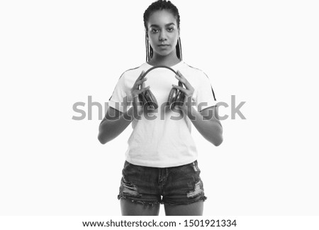 Portrait of beautiful african brunette teenage girl with dreadlocks in sportswear listening music via wireless headphones isolated on studio background