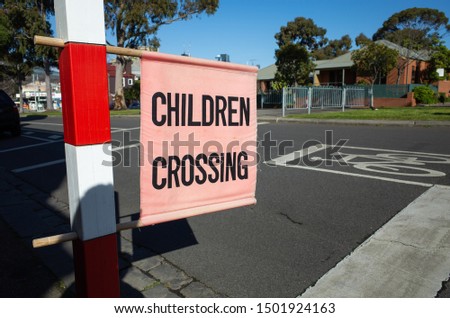 Flag of ‘Children Crossing’ on suburban street. Melbourne, VIC Australia. When displayed, drivers must not proceed through the crossing if children are still on the crossing or about to start crossing