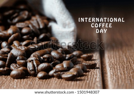 International coffee day wording on top right of the image and coffee beans on a wooden table