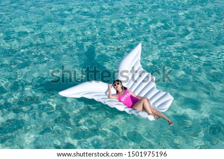 Luxury summer vacation beach woman relaxing lying down on inflatable pool float floating at Maldives sun tanning. Model sleeping on holiday.