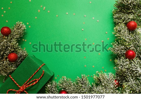 christmas wrapped gift box and tree branches on green background with confetti. new year concept. Greeting card, xmas celebration 2020. Flat lay, template, top view, copy space