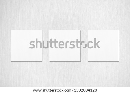 Three empty white square flyer or business card mockups with soft shadows on neutral light grey textured background. Flat lay, top view