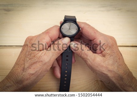 Hands of an elderly man hold a wristwatch. The concept of speed of time, transience of time, old age. Image. Royalty-Free Stock Photo #1502054444