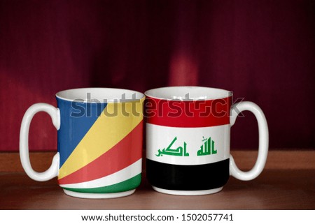 Iraq and Seychelles flag on two cups with blurry background