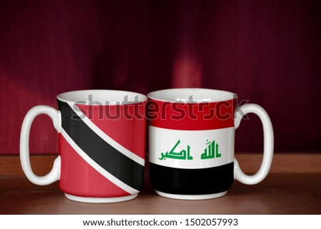 Iraq and Trinidad and Tobago flag on two cups with blurry background
