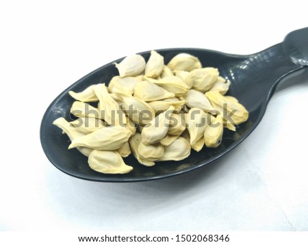 A picture of orange seed's on black spoon