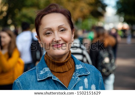 Older woman headshot. Nice street portrait of middle aged woman outdoors. 
