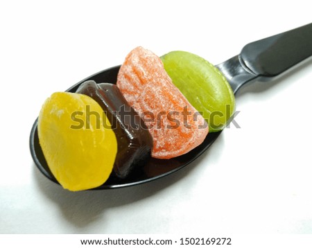 A picture of mixed candy's on black spoon