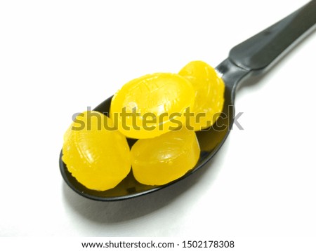A picture of mango flavour candy's on black spoon