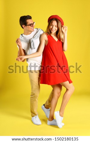 Beautiful young couple dancing on yellow background