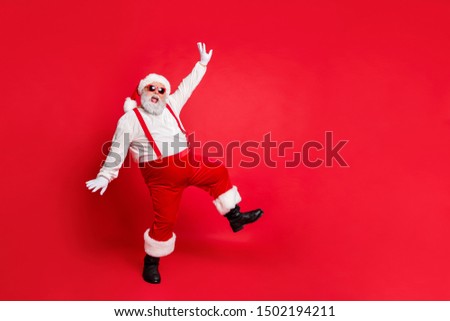 Full length photo of fat overweight santa claus with big funny belly abdomen have eyeglasses dancing wearing trousers pants boots isolated over red background