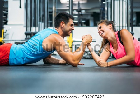 Two athletes doing arm wrestling challenge while lying on floor of gym