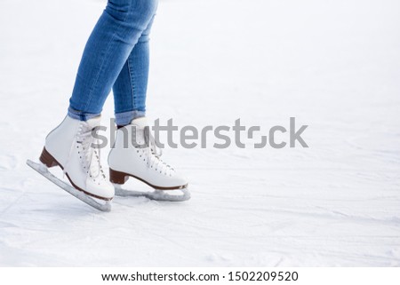 legs in white leather skates and copy space over white ice at rink