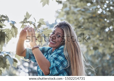 Young woman outdoors making heart - shape symbol for love and romance.