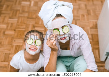 mother and daughter applying cosmetic face mask at home