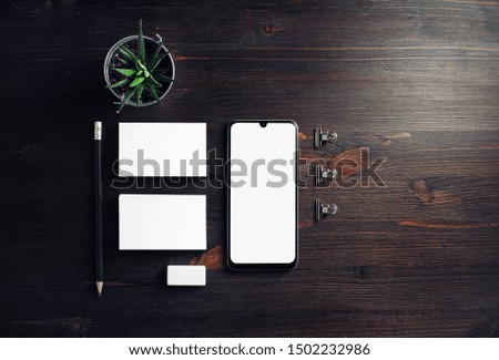 Cellphone and stationery on wooden background. Smartphone, business cards, pencil, eraser and plant. Flat lay.