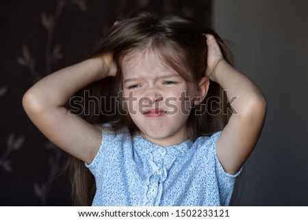 the girl is crying, grabbed her head, a child’s problems. The girl scratches her head, severe itching, infection with lice