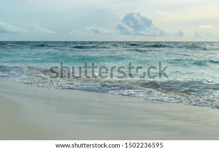 Foam of a turquoise ocean surf on the white sand of a tropical island. Foam texture background. Ocean wave. Maldives.
