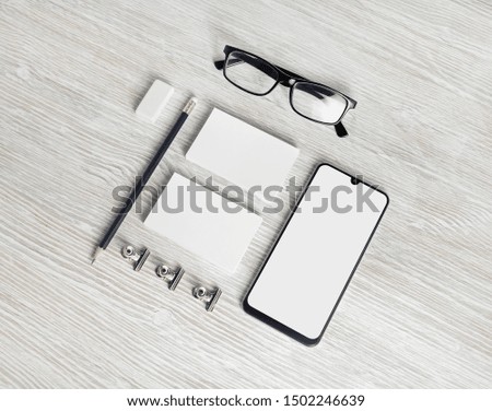 Photo of blank corporate identity. Stationery set. Branding mockup. Smartphone, business cards, pencil, eraser and glasses