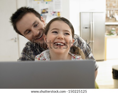 Loving father and daughter with laptop smiling together at home