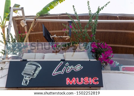 Bright neon sign live music with a neon microphone as a restaurant advertisement