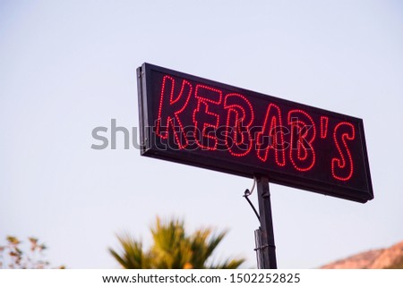 Bright red neon sign with Kebab inscription street food advertisement on sky background